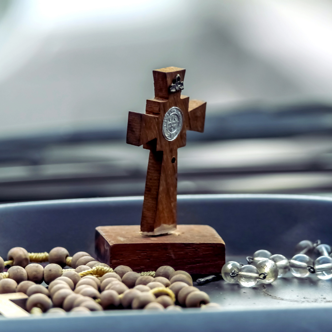 rosaries and small cross on car dashboard