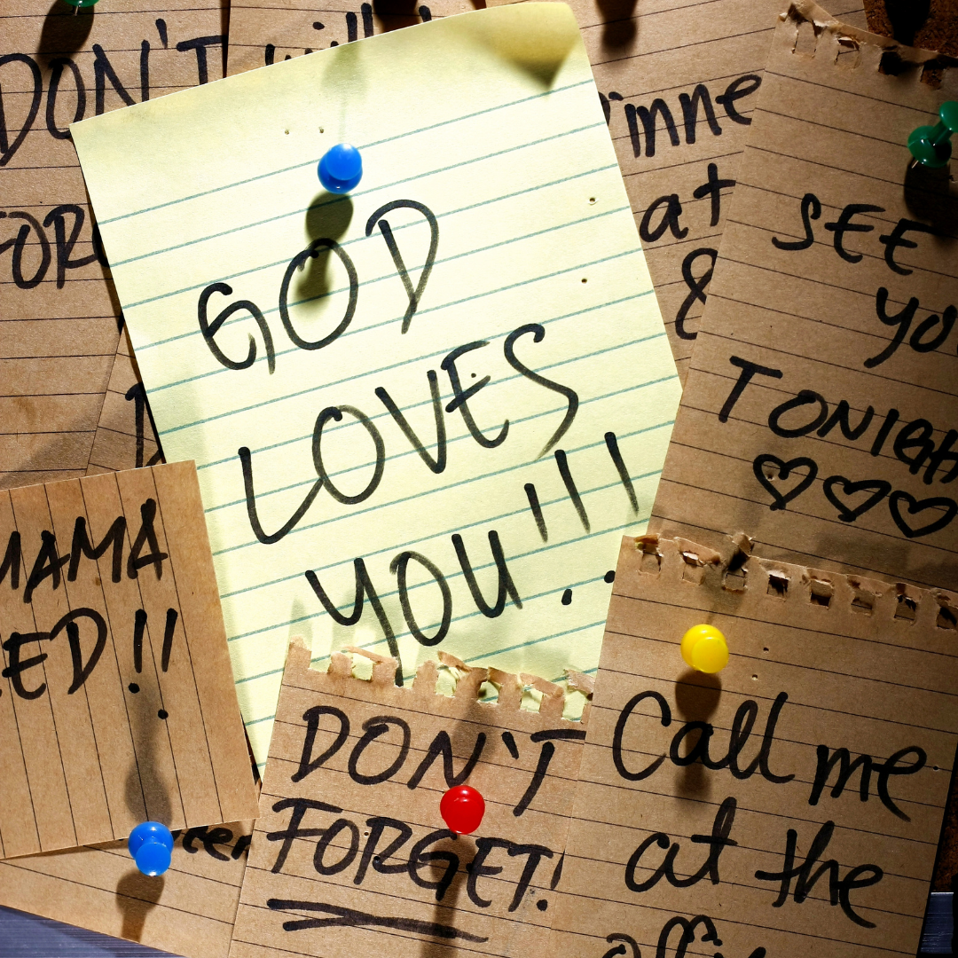 reminder notes on a bulletin board with "God loves you" in the center