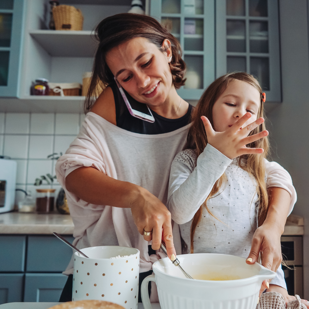 mom multitasking while she cooks with a little girl