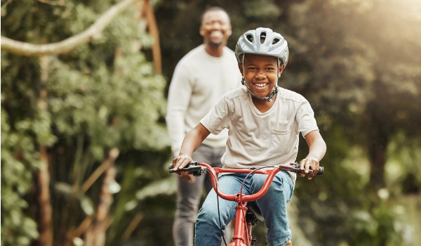 shot-of-an-adorable-boy-learning-to-ride-a-bicycle-with-his-father-picture-id1382489552